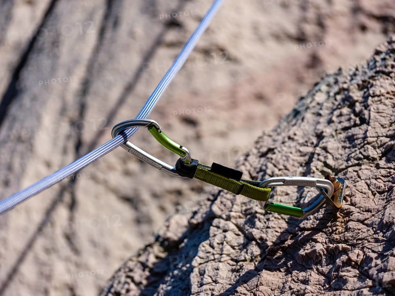 Climbing rope runs through a carabiner of an express sling, attached to a bolt, climbing area Belove Stene, island of Krk, Croatia, Europe
