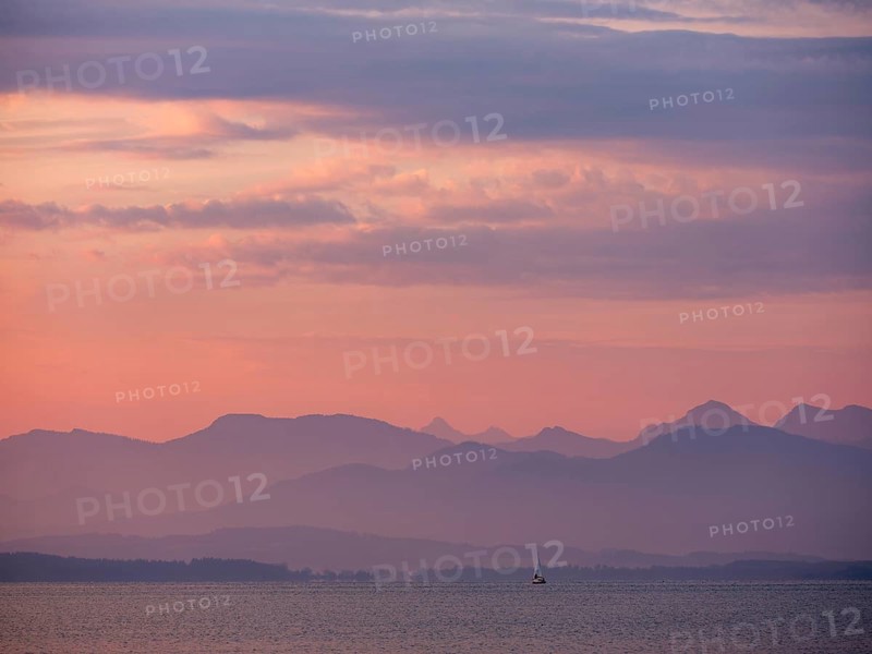 Small sailing boat on the Chiemsee in the morning light, behind the Chiemgau Alps, Chiemgau, Upper Bavaria, Bavaria, Germany, Europe