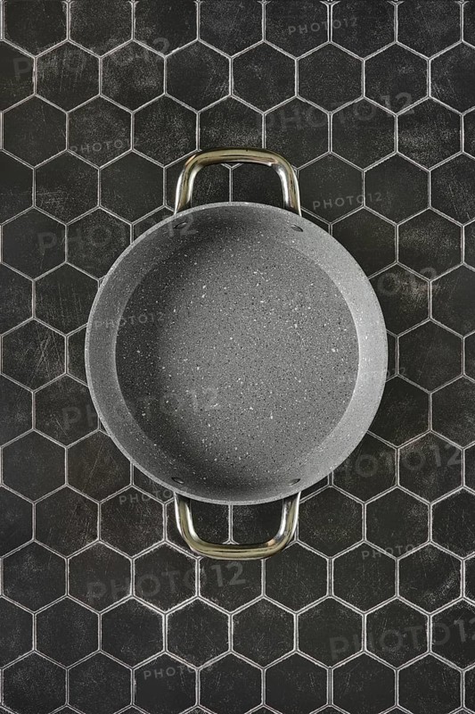 Top view of double handled non-stick frying pan on hexagon tile background