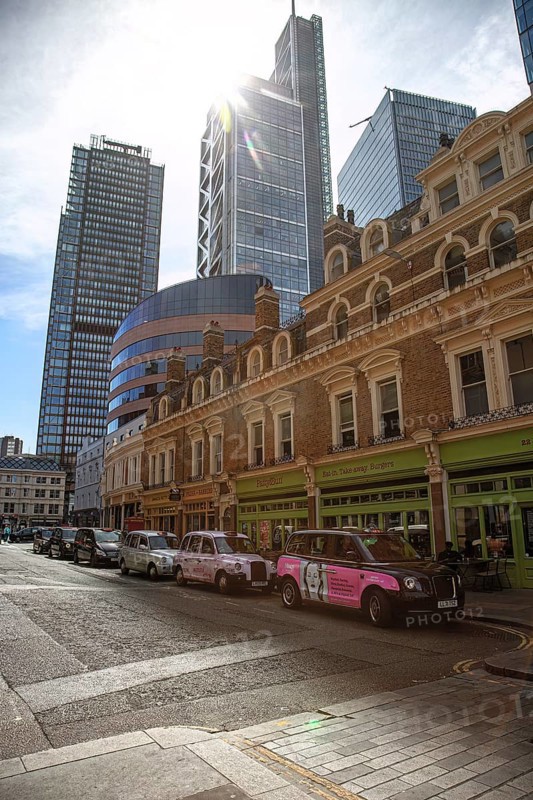City scene with historic buildings and modern skyscrapers in the sunlight in the foreground are typical London taxis, London, United Kingdom Great Britain