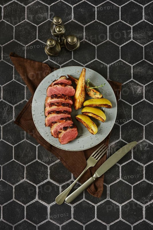 A spicy gourmet dish in which the duck breast is perfectly baked with golden apples and pears elegantly arranged on a plate