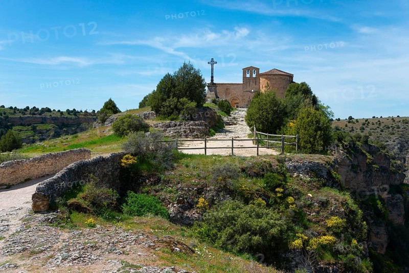 A small historic church with a stone cross on a hill surrounded by trees and a path in a peaceful landscape, Ermita de San Frutos, Natural Park of the Gorges of the Duratón River, Duraton, Parque Natural de las Hoces del Río Duratón, Sepulveda, Segovia, Valladolid, Castilla y León, Spain, Europe