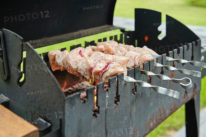 Cooking skewered pork meat on barbecue, close-up view