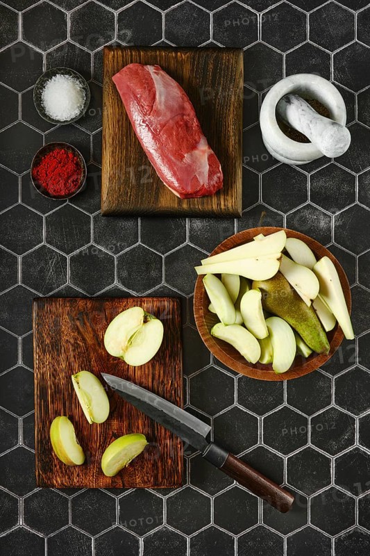 Overhead view of sliced apples and pears laid out on a chopping board next to the duck breast