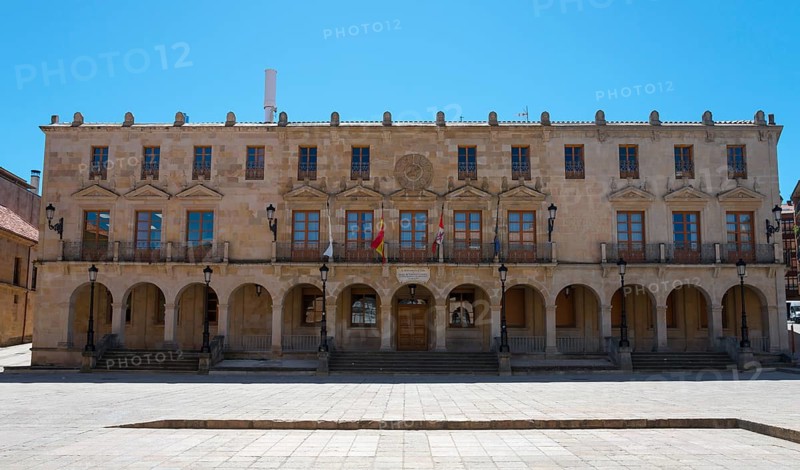 A large historic building with arcades and flags stretching across a spacious square under a blue sky, Ayuntamiento, Soria, Castilla y León, Leon, Spain, Europe