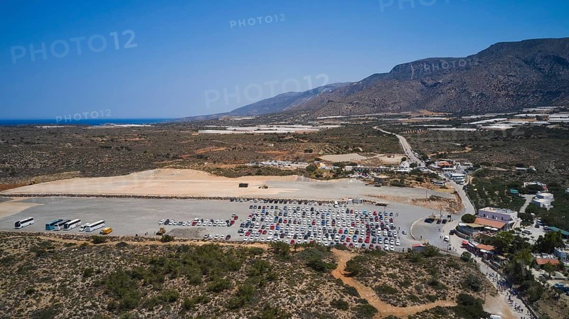 Overtourism, A large car park in the middle of an arid landscape, surrounded by mountains and a clear sky, Elafonissi, lagoon, south-western tip of Crete, Crete, Greek Islands, Greece, Europe
