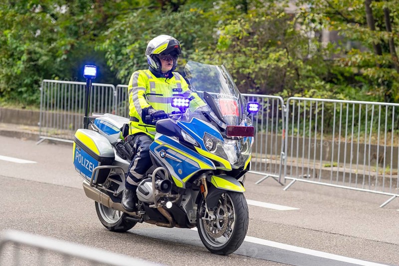 A police officer rides a motorbike with blue lights during an operation, surrounded by barriers on a road, Stuttgart, Baden-Württemberg, Germany, Europe