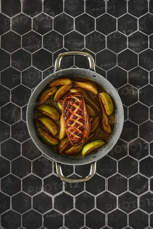 Savory perfectly seared duck breast with caramelized tender apples and pears in a rustic baking pan
