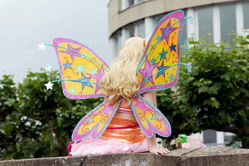Costumed woman with butterfly wings sitting on a wall, back view, cosplay at Japantag Düsseldorf, North Rhine-Westphalia, Germany, Europe