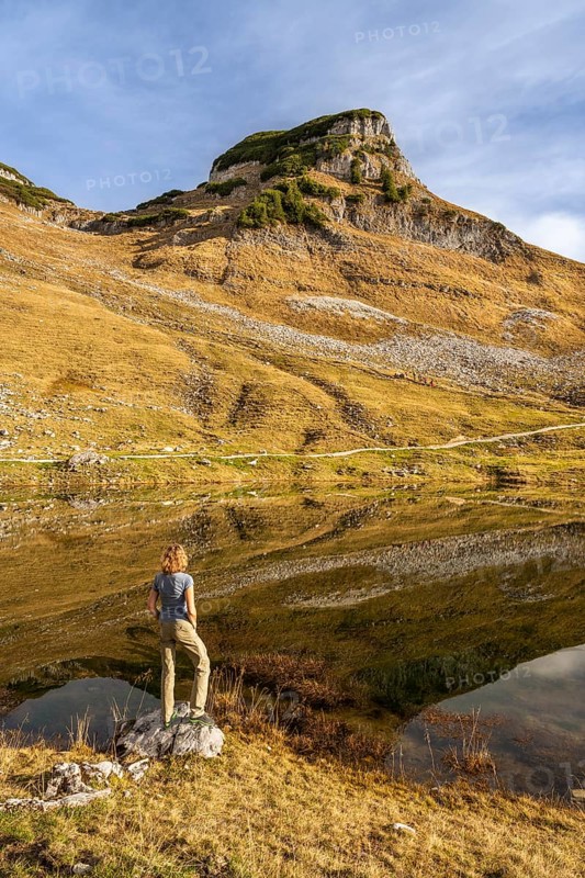 Lake Augstsee and the Atterkogel mountain on the Loser. A hiker stands on the shore. Autumn, good weather, blue sky. Reflection. Altaussee, Bad Aussee, Ausseer Land, Totes Gebirge, Styria, Upper Austria, Austria, Europe