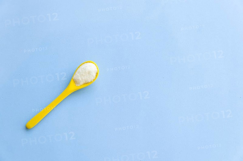 Spoon with sugar close-up on a light blue background
