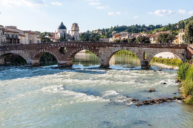 View of Verona historical city centre, Ponte Pietra bridge across Adige river, Verona Cathedral, Duomo di Verona, red tiled roofs, Veneto Region, Italy. Verona cityscape, panoramic view