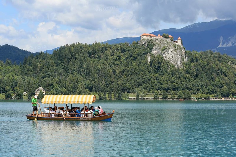 SLOVENIA, BLED, JULY 15, 2019: Traditional turist boat. Beautiful mountain lake in summer with castle on cliff and alps in the background