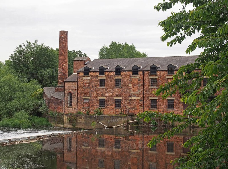 Thwaite mill leeds built in 1825 on an island between the river aire and calder navigation canal reflected in the water and surrounded by trees