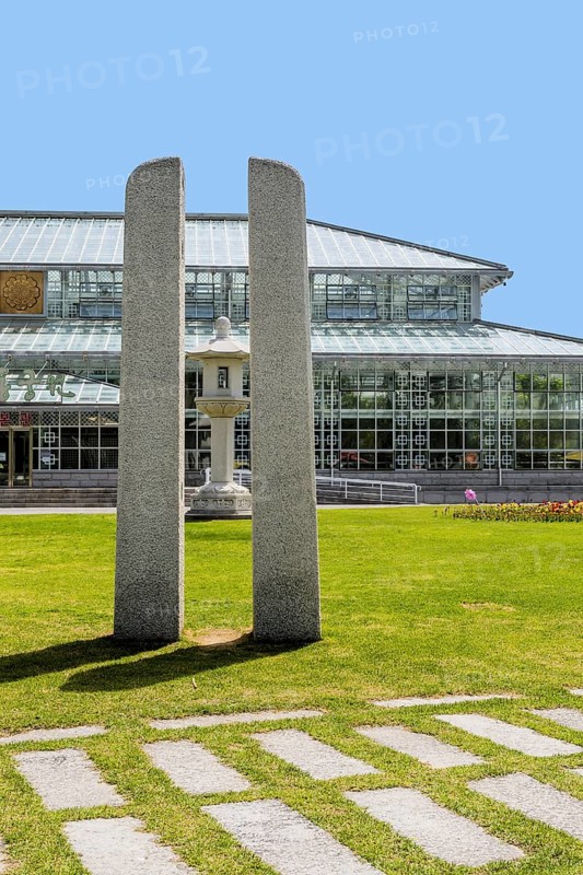 Modern architectural glass building with central stone sculpture, amid a green park setting and clear blue sky in Gyeongju, South Korea, Asia