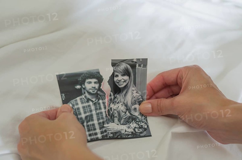 Great concept of divorce, betrayal, separation, woman hand ripping photo of the couple