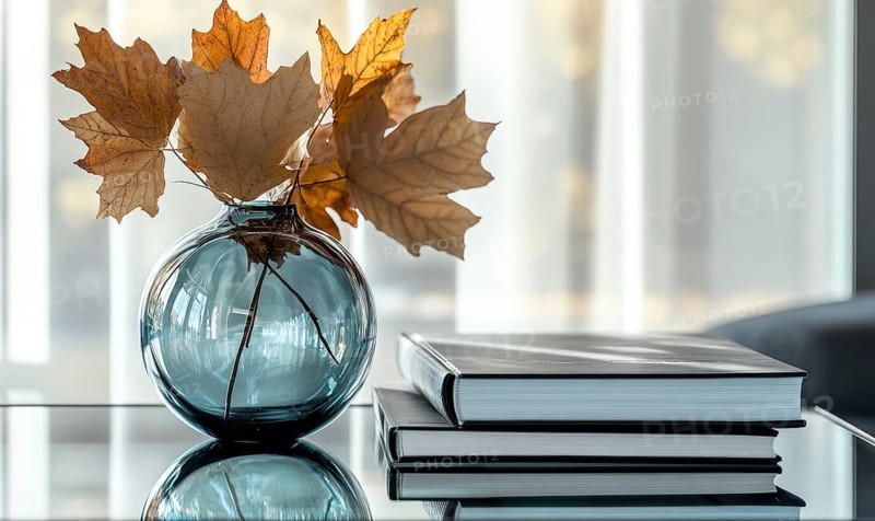 Minimalist table with a couple of books and a vase filled with vibrant autumn leaves AI generated