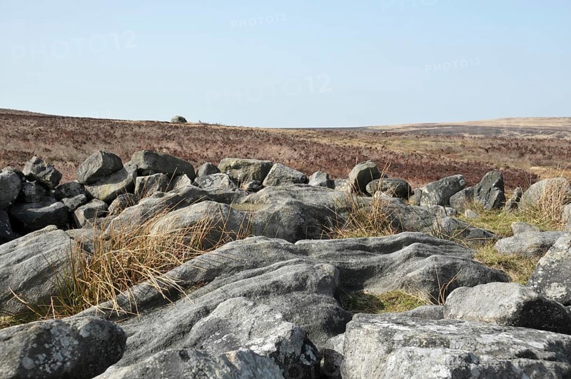 Exposed stones at the top of a cairn known as the millers grave on midgley moor in calderdale west yorkshire with pennine moorland scenery