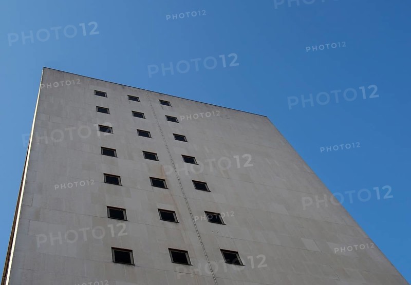 Perspective corner view of an old white 1960s concrete office block against a blue sky