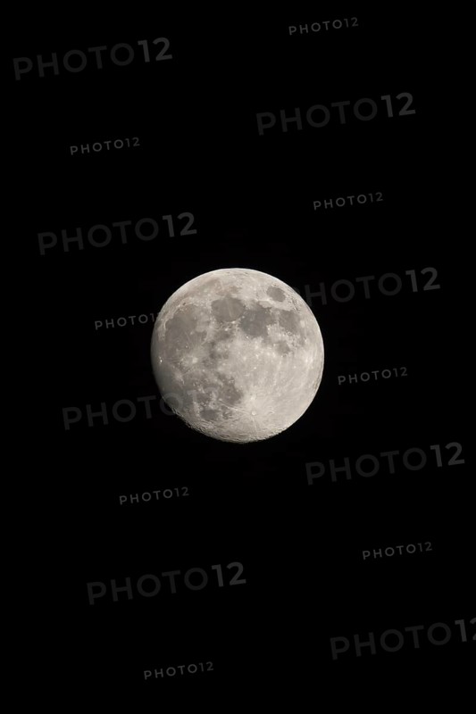 Waxing gibbous Moon, portrait orientated image in photo dimensions with Moon isolated on black background with text or copy space