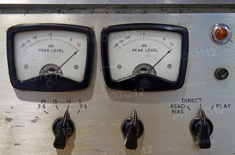 A close up of two old decibel meters on an old vintage reel to reel tape recorder with control knobs and switches