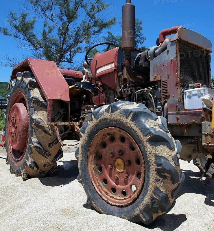 A rusting and corroded old tractor is parked on a sand beach