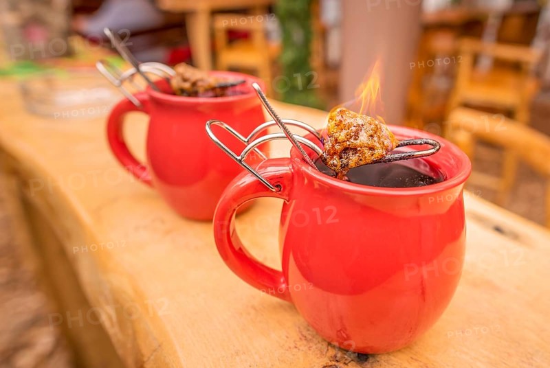 Image with a mug of hot wine, which has tongs with a flaming cone of sugar on top. It is a traditional german drink at Christmas fairs, called
