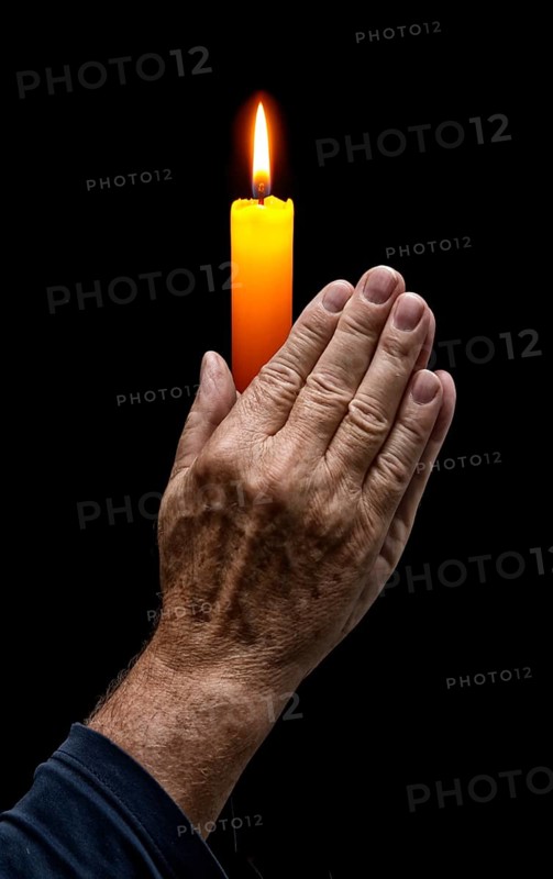 Praying hands with a candle