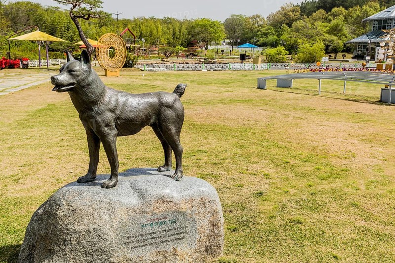A statue of a standing dog on a stone base in a garden park on a bright, sunny day in Gyeongju, South Korea, Asia