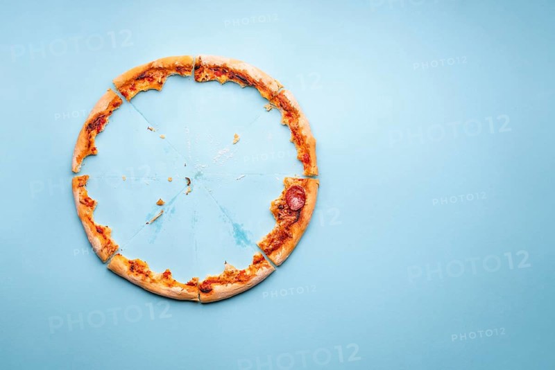 Pizza pepperoni leftovers top view on a blue background. Homemade pizza remainings and traces of grease on cardboard
