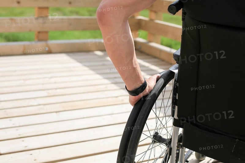 Disabled young man on a wheelchair holding and turning wheels with hand