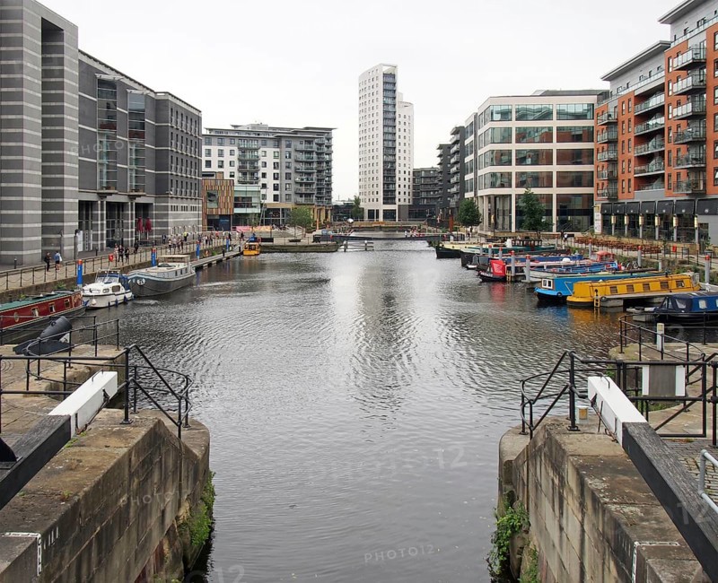 Leeds, west yorkshire, united kingdom, 4 july 2019: a view of leeds dock from the lock gates with houseboats moored next to waterside buildings