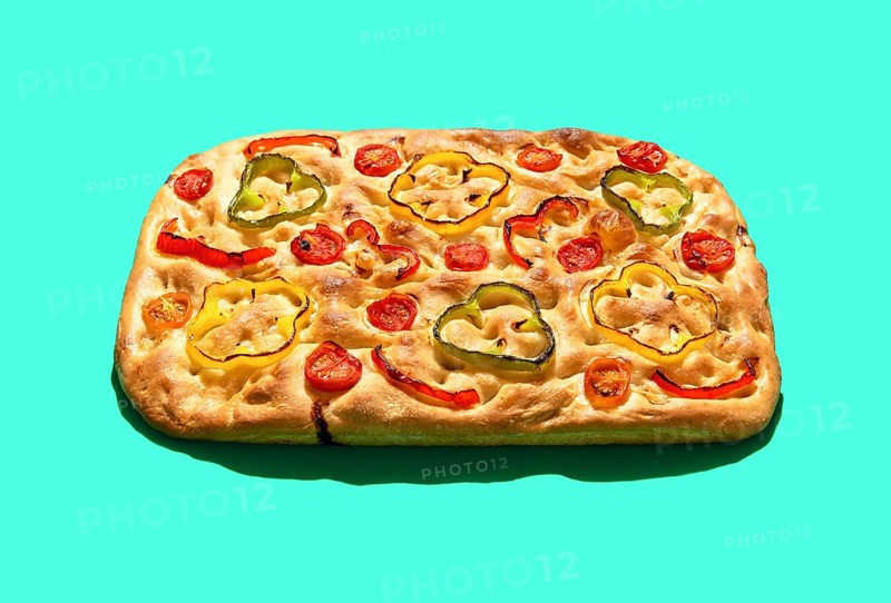 Homemade focaccia with vegetables and sourdough, in bright light minimalist on a green table. Delicious vegan focaccia isolated on a colorful background