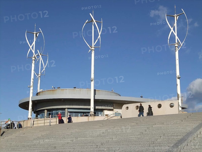 Blackpool, Lancashire, United Kingdom, 4 March 2022: people on the promenade walkway along the seafront at cleveleys in blackpool with the cafe and modern wind turbines, Europe