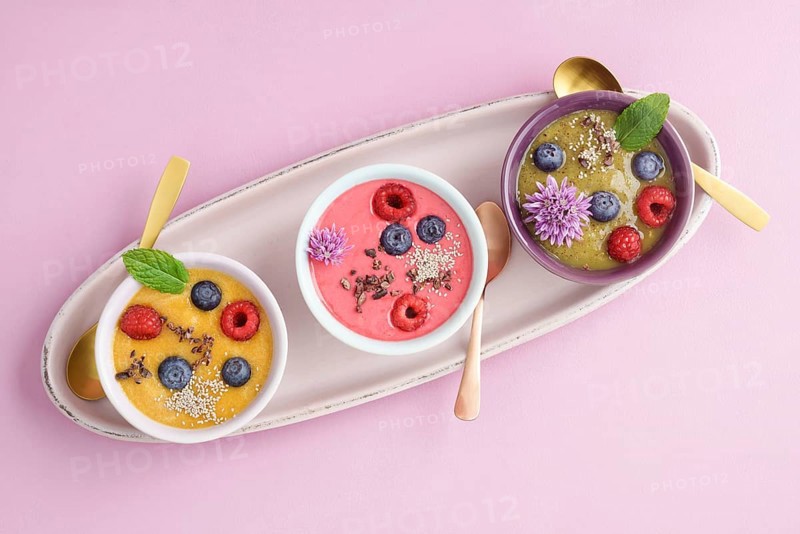 Three smoothie bowls with blueberries, raspberries, kiwi and peach