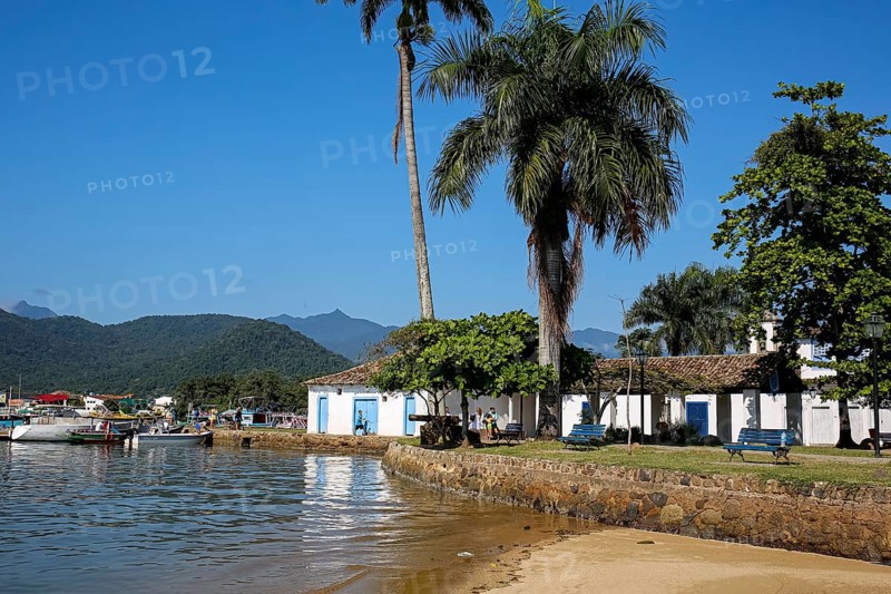 View to waterfront in historic town Paraty with colonial buildings, trees, sea and Atlantic forest mountains, Brazil, Unesco World Heritage, South America