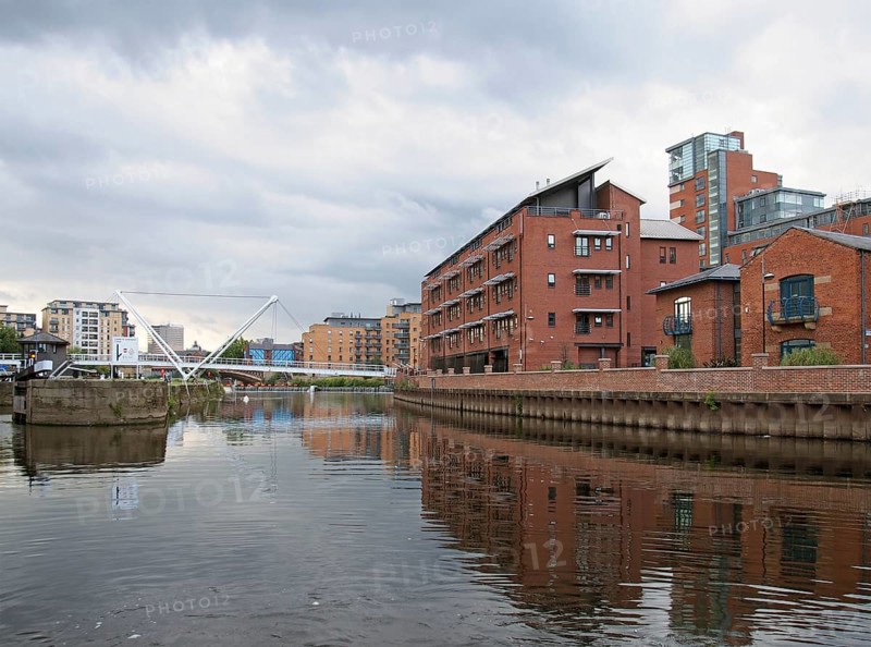 Leeds, west yorkshire, united kingdom, 10 july 2019: the river aire joined to the leeds liverpool canal in the clarence dock area with buildings reflected in the water locks and bridges