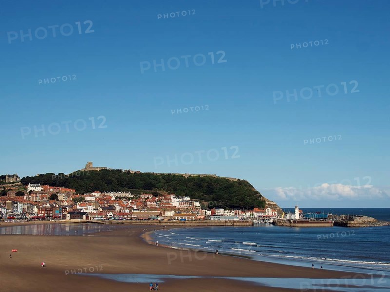 View of scarborough south bay with beach and town on a sunlit summer day with the harbour and castle in the distance