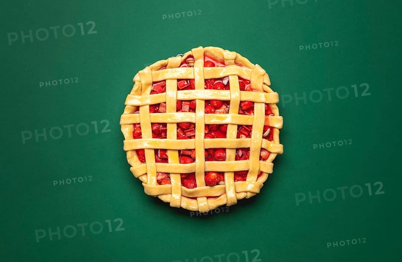 Strawberries and rhubarb pie with a lattice crust, above view on a green background. Top view with a lattice crust fruitcake