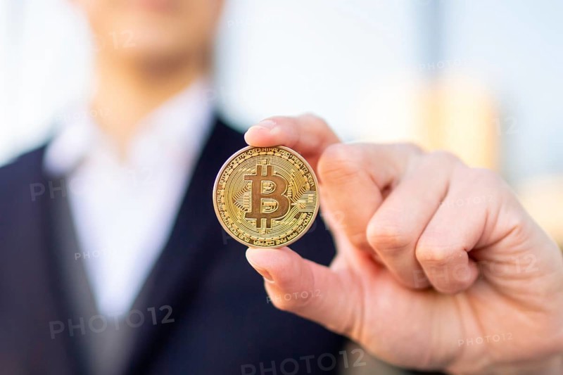 Bitcoin cryptocurrency coin in a young businessman hand. Disruptive blockchain technology concept and transfer of wealth