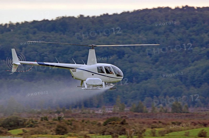 Helicopter spraying fertiliser on a crop in Westland, New Zealand, Oceania