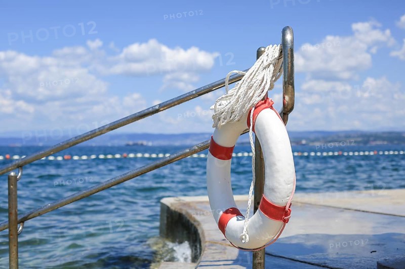 Emergency lifebuoy hanging on fence near sea at beach