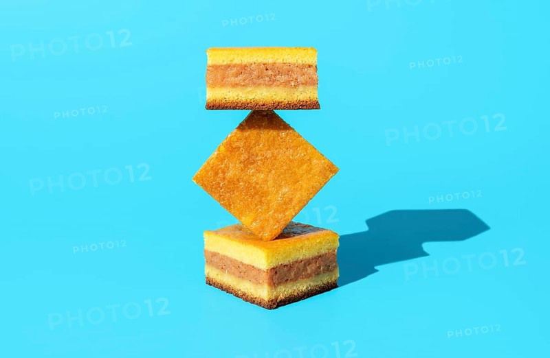 Homemade apple cake in bright light, minimalist on a blue table. Slices of apple cake in an abstract shape stack