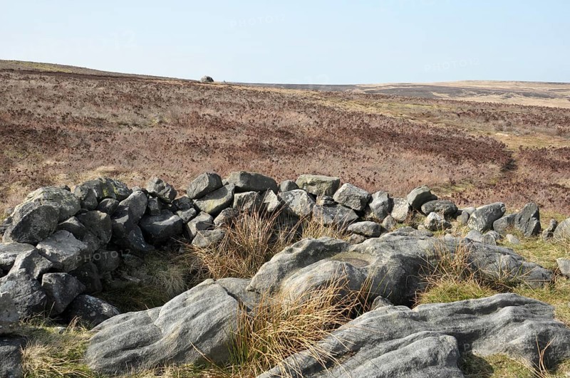 Exposed stones at the top of a cairn known as the millers grave on midgley moor in calderdale west yorkshire with pennine moorland scenery