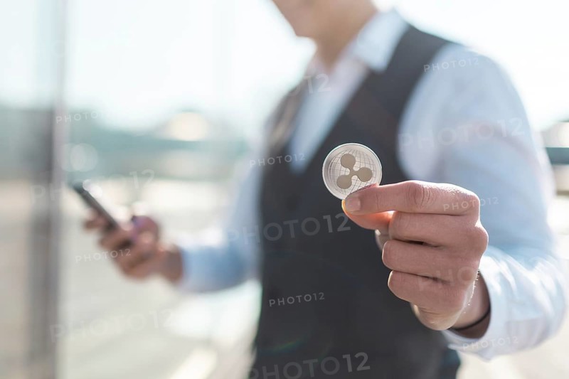 Ripple cryptocurrency coin in a young businessman hand. Disruptive blockchain technology concept and transfer of wealth