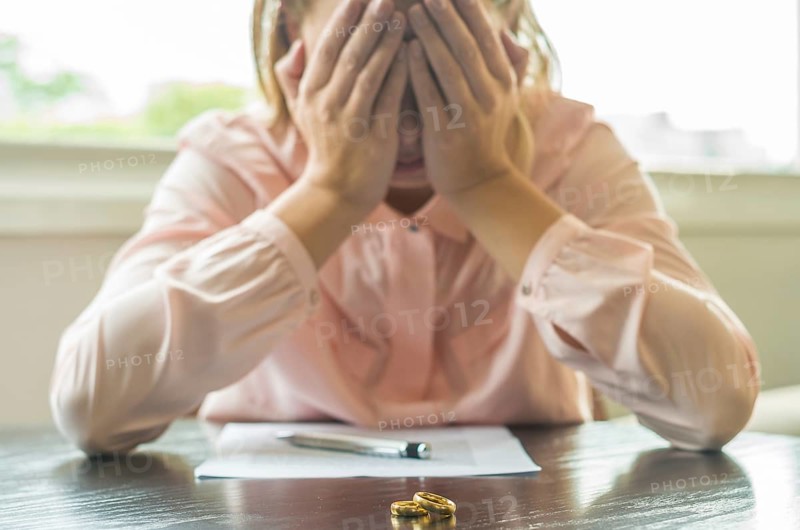 Great concept of divorce, end of relationship, sad young woman, signing divorce agreement, with hands in the face