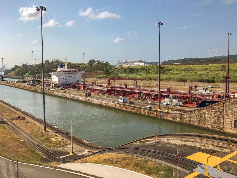 Scene in an industrial area with a large ship in the canal surrounded by containers and buildings. The sky is clear, panama city, panamakanl, panama, Central America