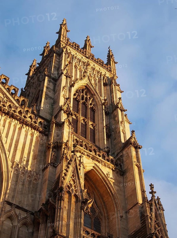 Side view of one of the towers at the front of york minster in sunlight against a blue cloudy sky