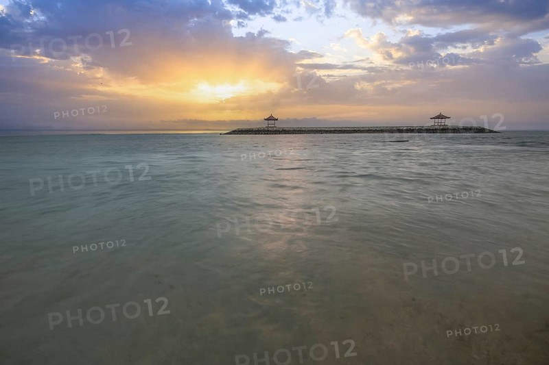Beautiful seascape in the morning. Tropical sandy beach with breakwater and reflection of the sky in the calm water. Morning landscape, taken in Sanur, Bali, Indonesia, Asia