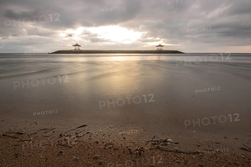 Beautiful seascape in the morning. Tropical sandy beach with breakwater and reflection of the sky in the calm water. Morning landscape, taken in Sanur, Bali, Indonesia, Asia